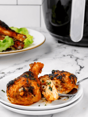 Air fryer buffalo chicken drumsticks coated in spicy sauce with crispy golden skin