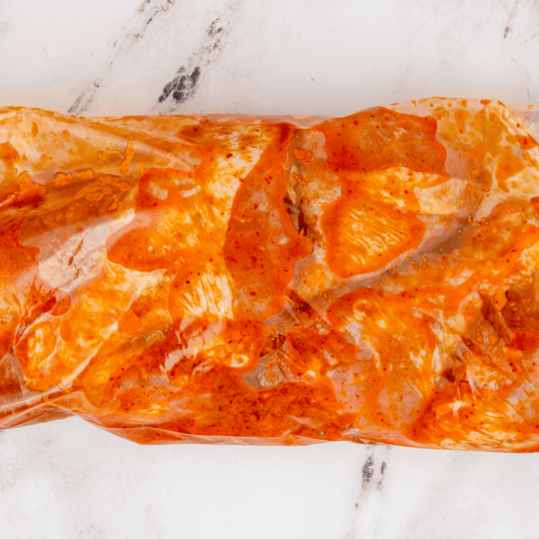 Raw chicken drumsticks coated in cornstarch and spice rub before going in the air fryer.