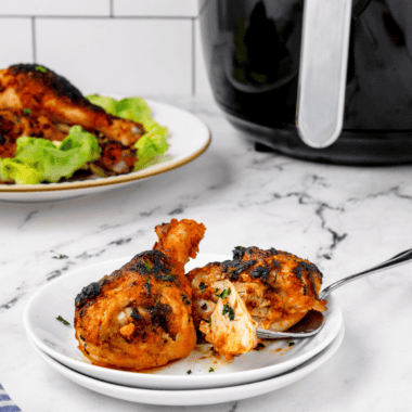 Air fryer buffalo chicken drumsticks coated in spicy sauce with crispy golden skin