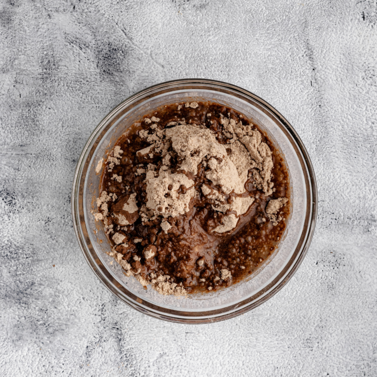 Mixing brownie batter with eggs, oil, and water in a bowl until smooth and well combined.