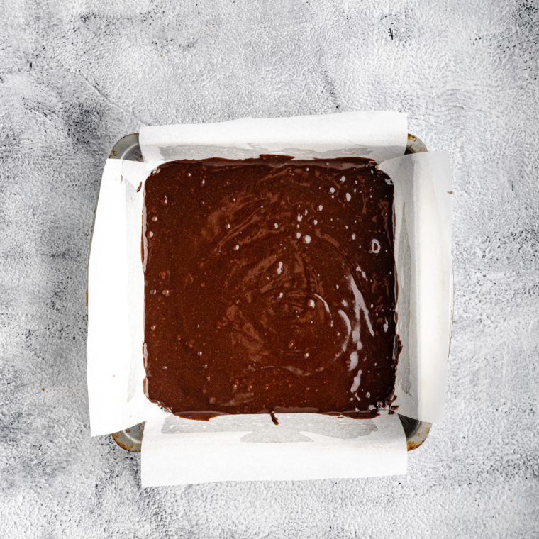 Layering brownie batter with mini marshmallows and chocolate chips in a prepared baking pan.