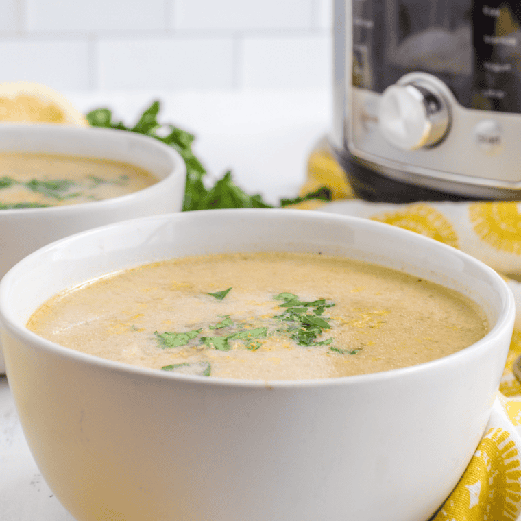 Two bowls of Instant Pot Greek lemon chicken soup (avgolemono) with rice, shredded chicken, fresh dill, and lemon slices