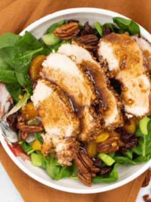 A bowl of fall-inspired salad featuring pecan-crusted chicken, crisp apples, pecans, and goat cheese.