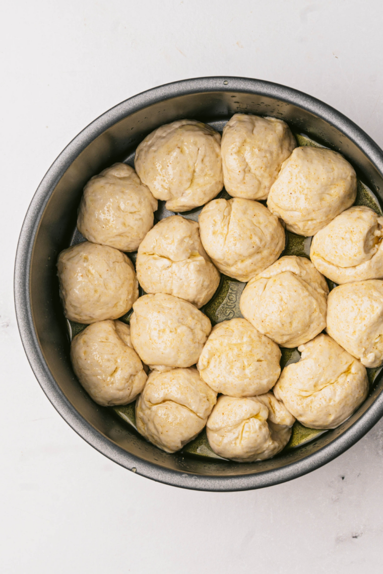 Biscuit dough pieces cut into quarters inside large mixing bowl