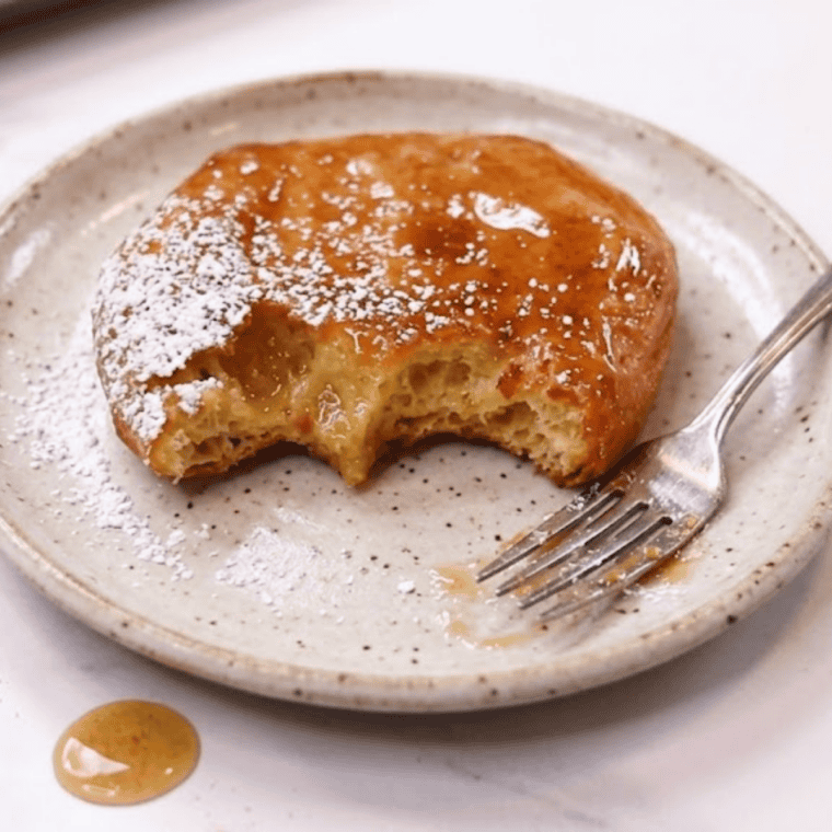 Air fryer fry bread topped with honey and powdered sugar on a rustic serving tray.