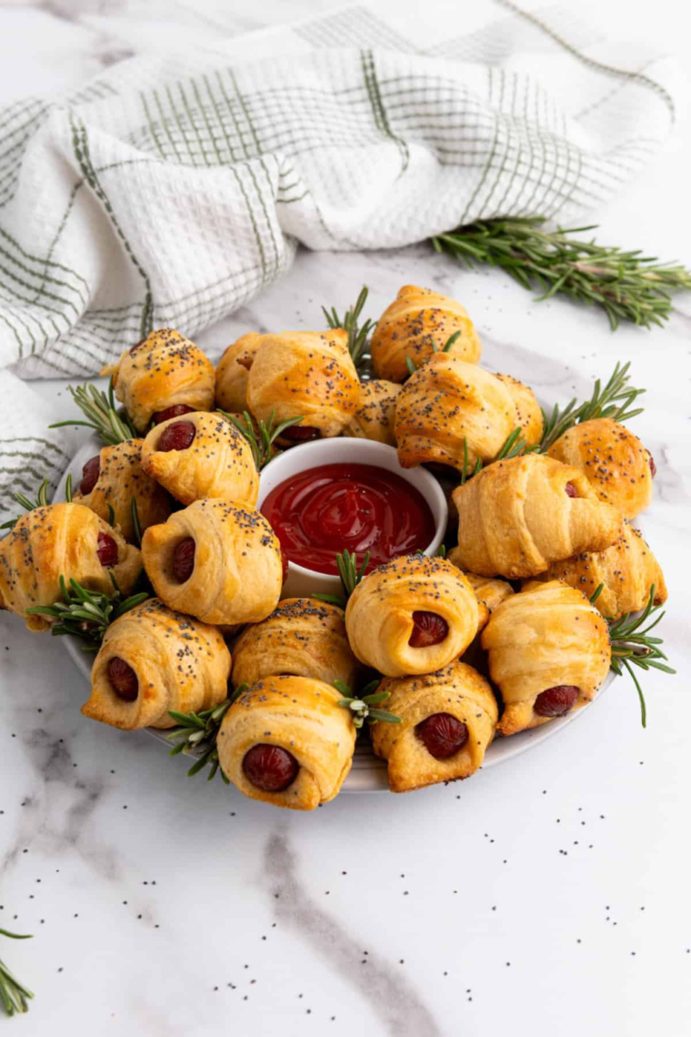 "Golden brown Air Fryer Pigs in a Blanket arranged on a plate, ready to be served with dipping sauces."