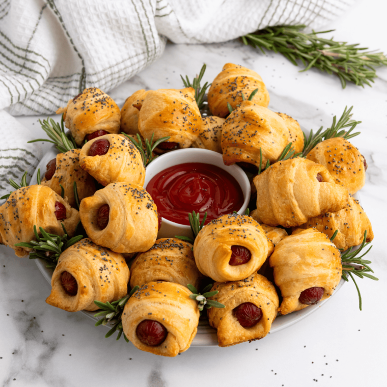 Plate of golden brown Air Fryer Pigs in a Blanket, crispy and ready to be enjoyed, served with dipping sauces.