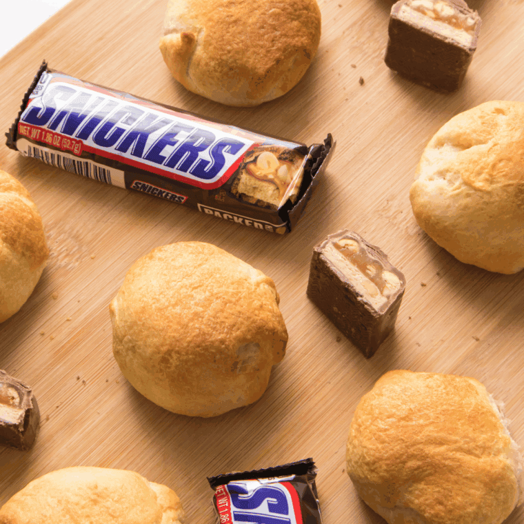 Air fryer Snickers bars with a golden crust, melted chocolate and caramel oozing out.