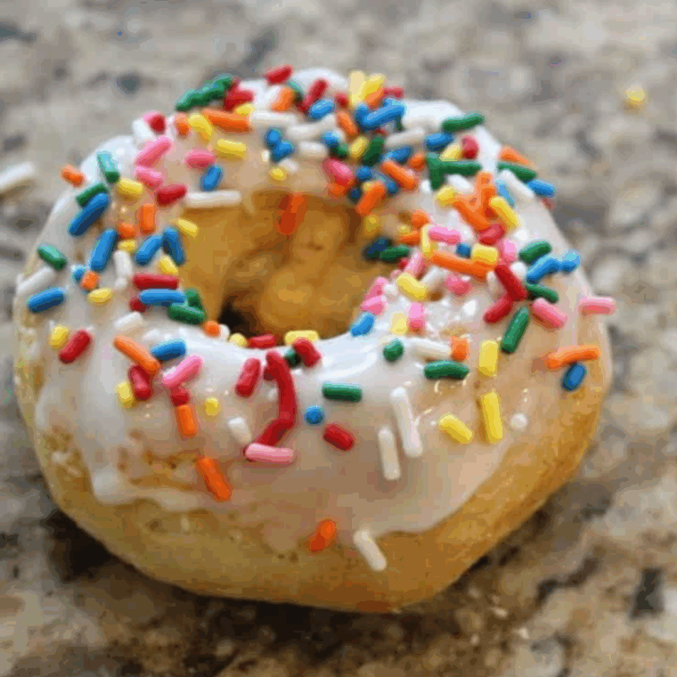 Homemade Dunkin’ Donuts sprinkle donuts with glaze and rainbow sprinkles on a plate.