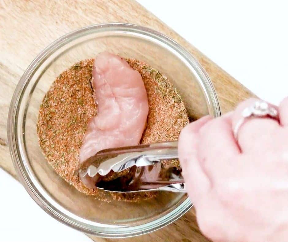 Close Up of the Chicken Being Dipped In Seasoning Blend How To Make Air Fryer Naked Chicken Tenders
