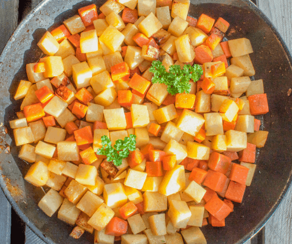 Air Fryer Roasted Potatoes and Carrots in a large black serving dish. The vegetables have been cut into small cubes and are garnished with fresh Parsley.