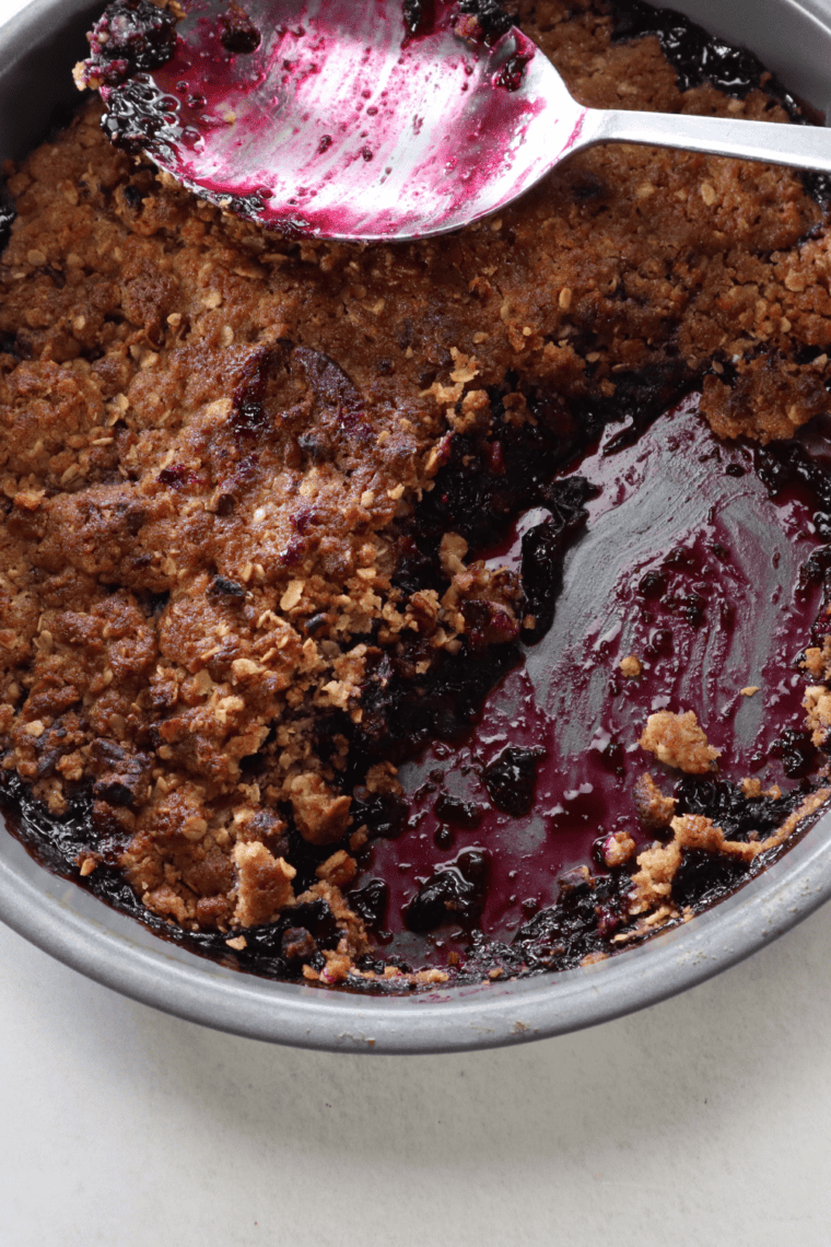 Showing the juicy filling: Serving of blueberry crisp with bubbling berry filling and crisp oat topping