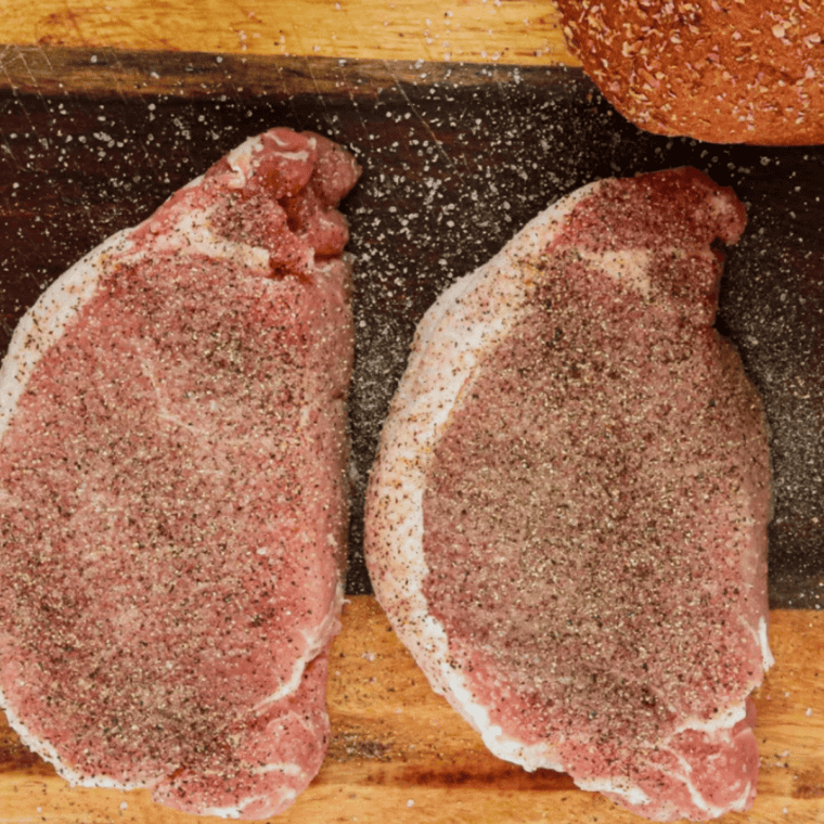 Boneless pork chops seasoned with salt and pepper before air frying