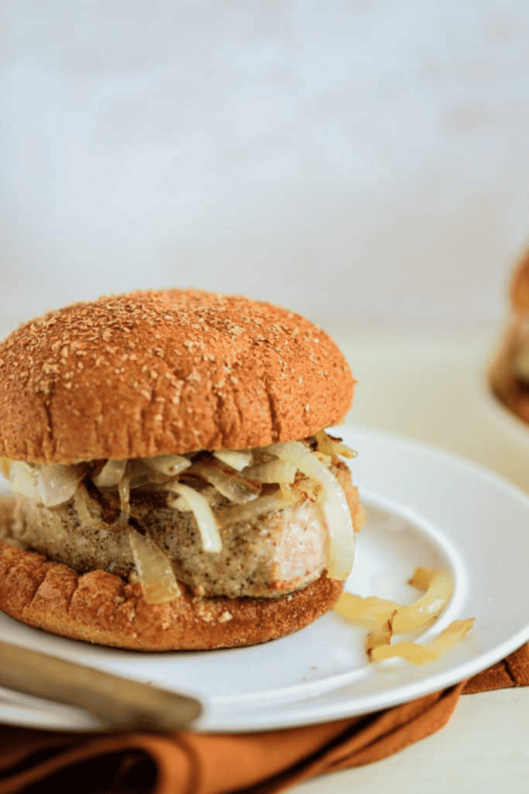 Close-up of a juicy air fryer pork chop sandwich topped with caramelized onions