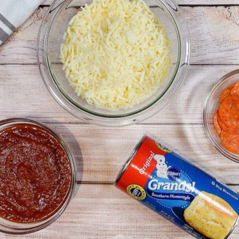 Ingredients for pizza casserole laid out on a wooden table.