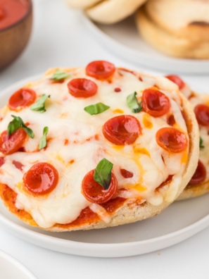 Air fryer English muffin pizzas topped with melted cheese and various toppings, cooked to crispy perfection in minutes."