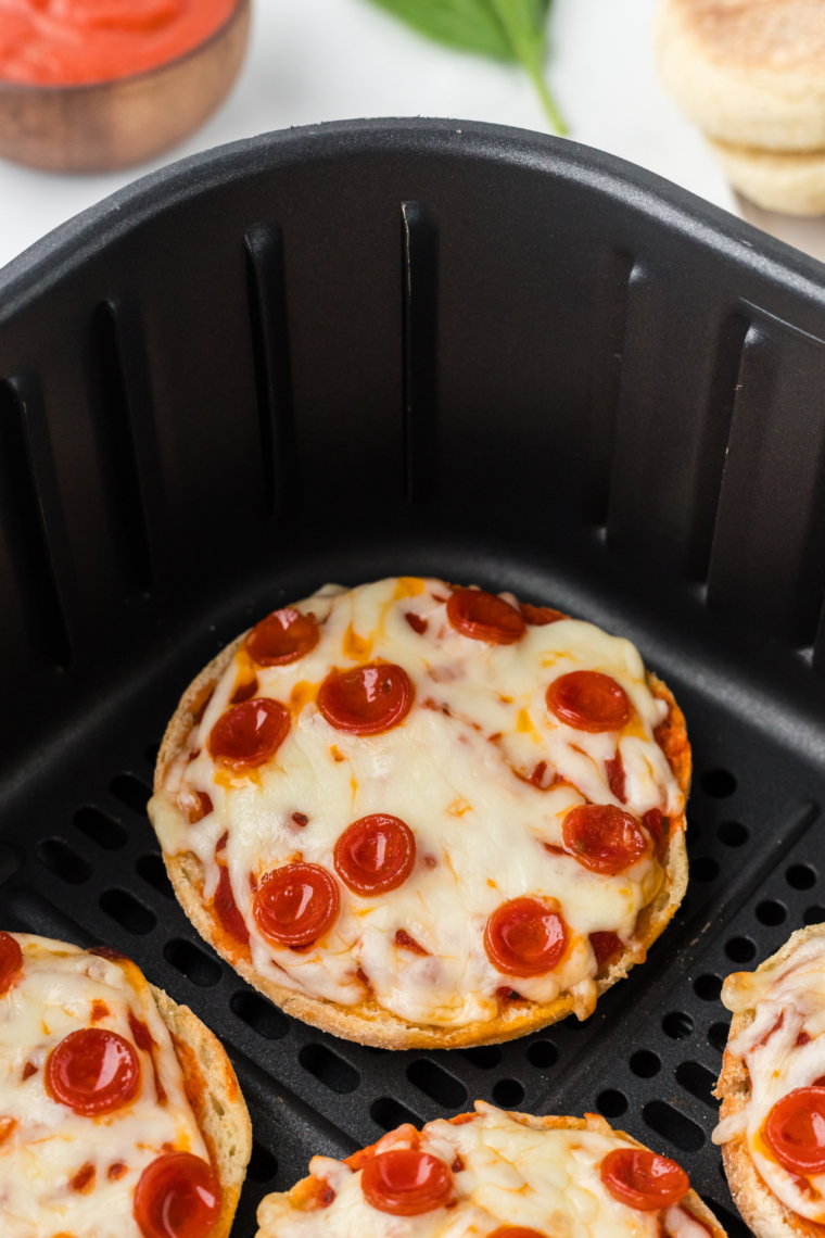 Air fryer English muffin pizzas topped with sauce, cheese, and fresh ingredients, cooked to perfection in the air fryer.