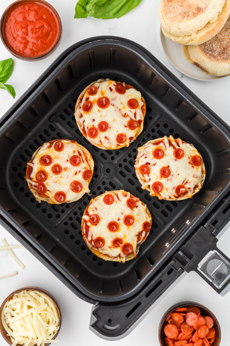 Air fryer English muffin pizzas topped with melted cheese and a variety of fresh toppings, cooked to crispy perfection.