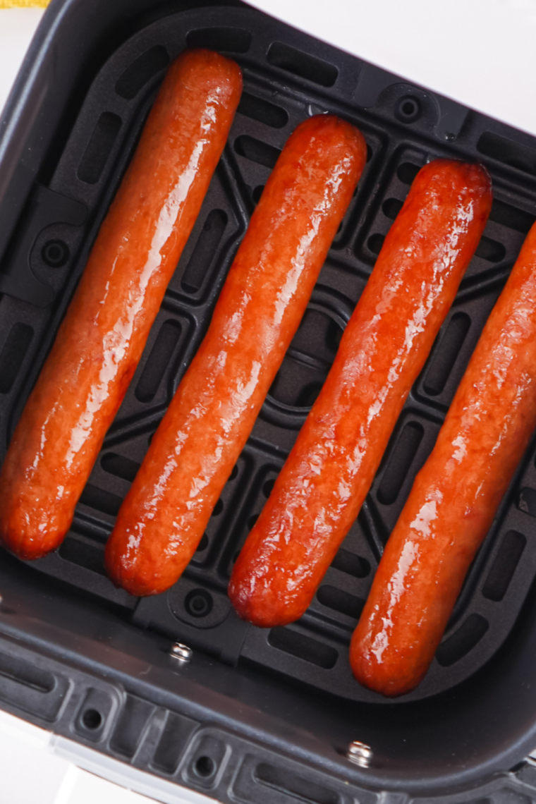 Hot dogs in buns toasting in air fryer until warm and lightly crisp.