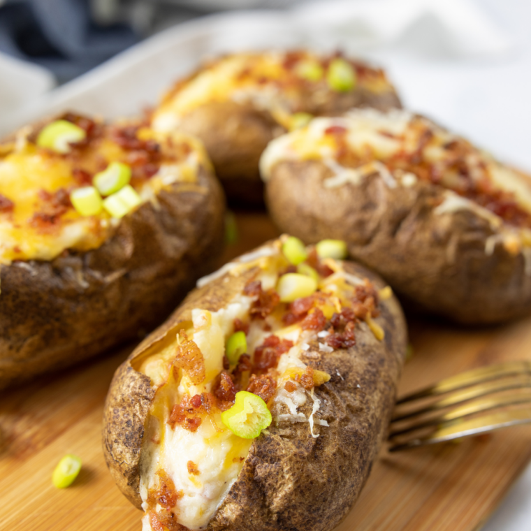 Plate of whole air fryer jacket potatoes with crisp, salted skins
