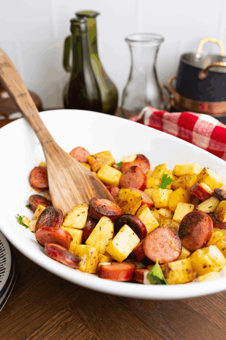 Air fryer kielbasa and potatoes cooked to golden crisp in air fryer basket.