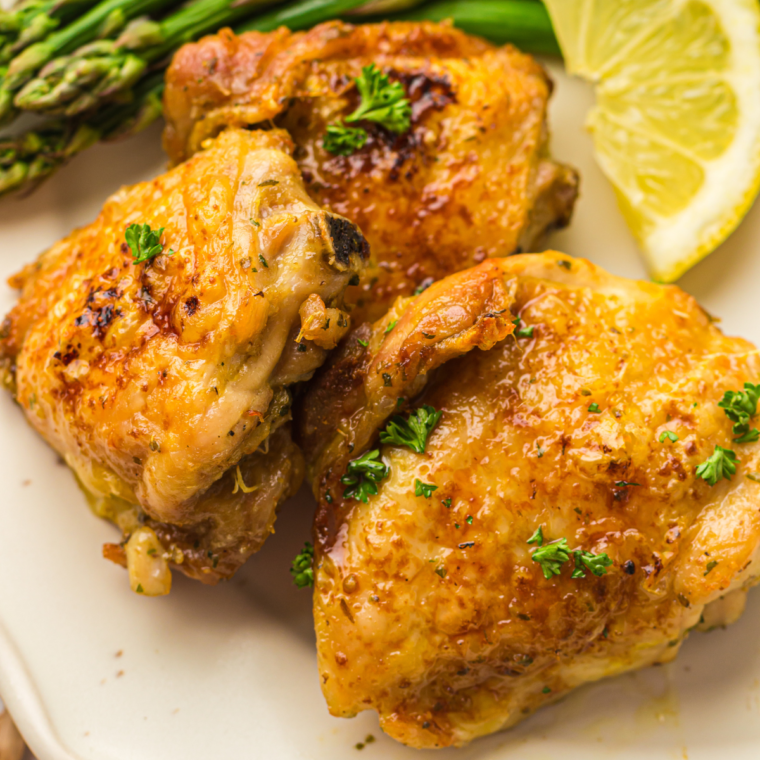 Golden brown air fryer ranch chicken thighs on a plate garnished with fresh herbs.
