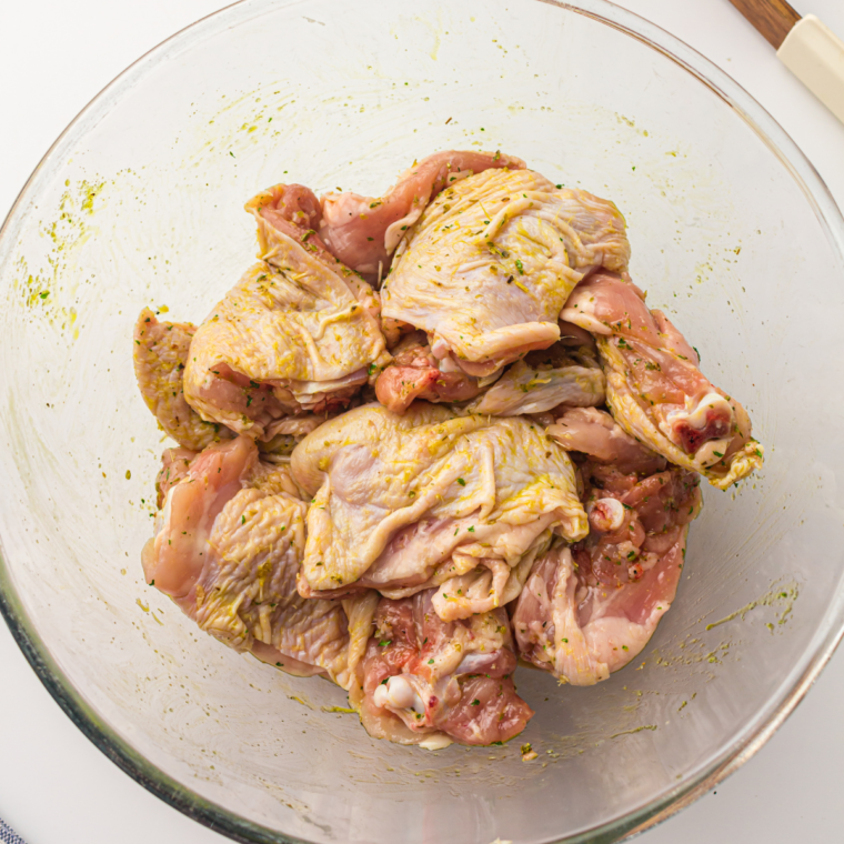 Ranch-seasoned chicken thighs arranged in a single layer in an air fryer basket, ready to cook.