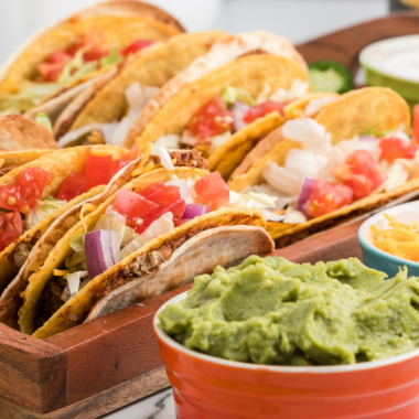 Air fryer steak tacos filled with sliced marinated ribeye, topped with lettuce, tomato, and cheese in warm tortillas