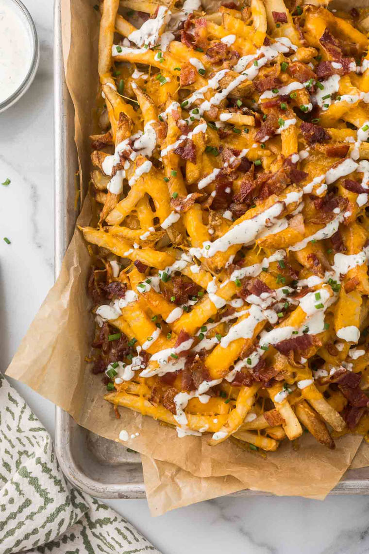 Layering fries with shredded cheddar, Monterey Jack, and crumbled bacon in a skillet for Chili's Texas Cheese Fries