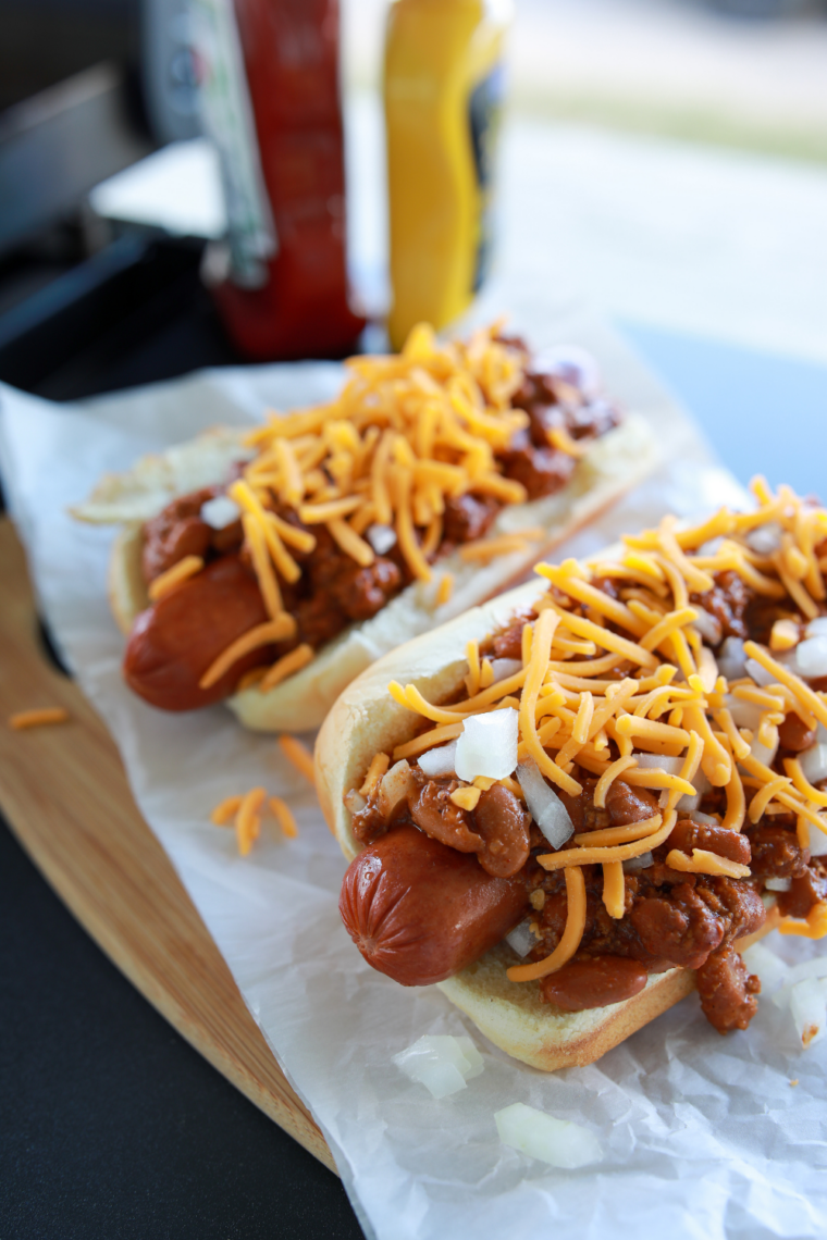 Hot dogs cooking in a Ninja Crispi air fryer basket with crispy browned edges and juicy centers ready to serve in buns.