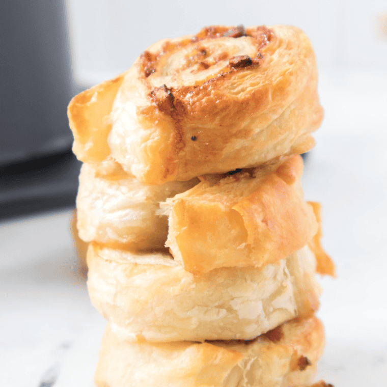 Flaky air fryer breakfast pinwheels stuffed with scrambled eggs, cheese, and bacon, served warm on a white plate