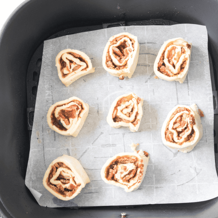 Uncooked breakfast rolls in the air fryer basket.