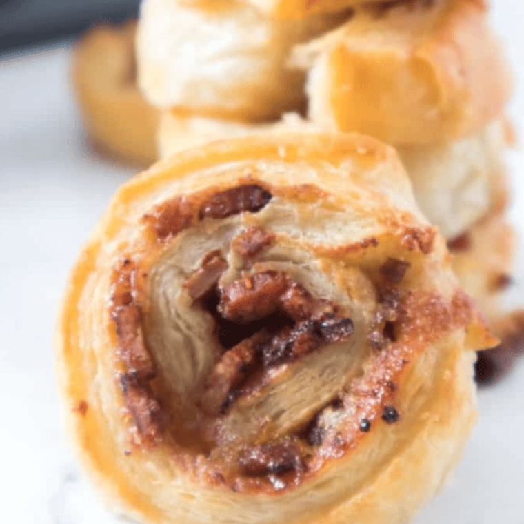 Golden brown air fryer breakfast pinwheels filled with bacon, cheddar cheese, and a hint of brown sugar, served hot on a white plate