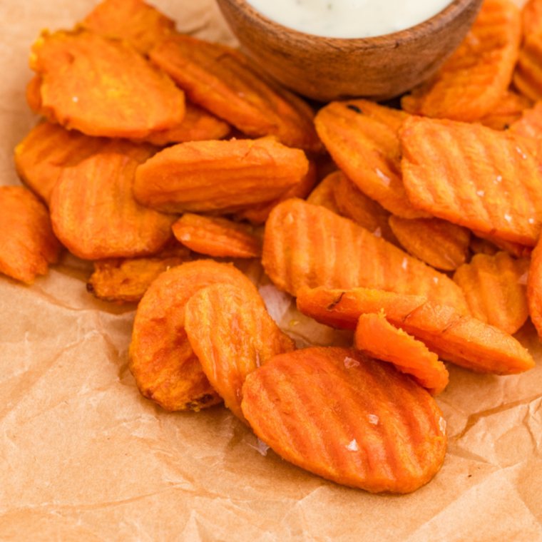 A close-up of crispy air-fried carrot chips being checked for doneness with a fork.