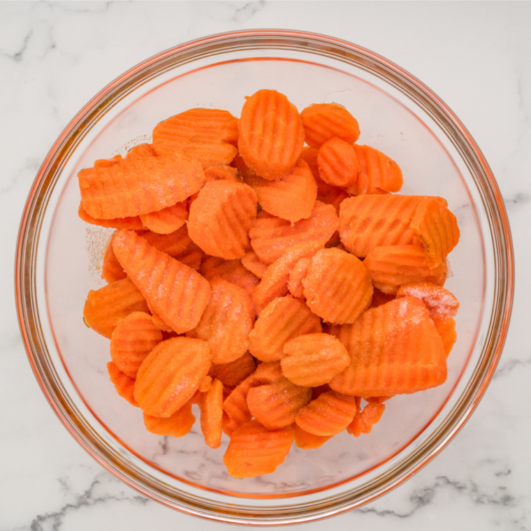 Fresh carrots being washed and peeled on a cutting board, ready for slicing.