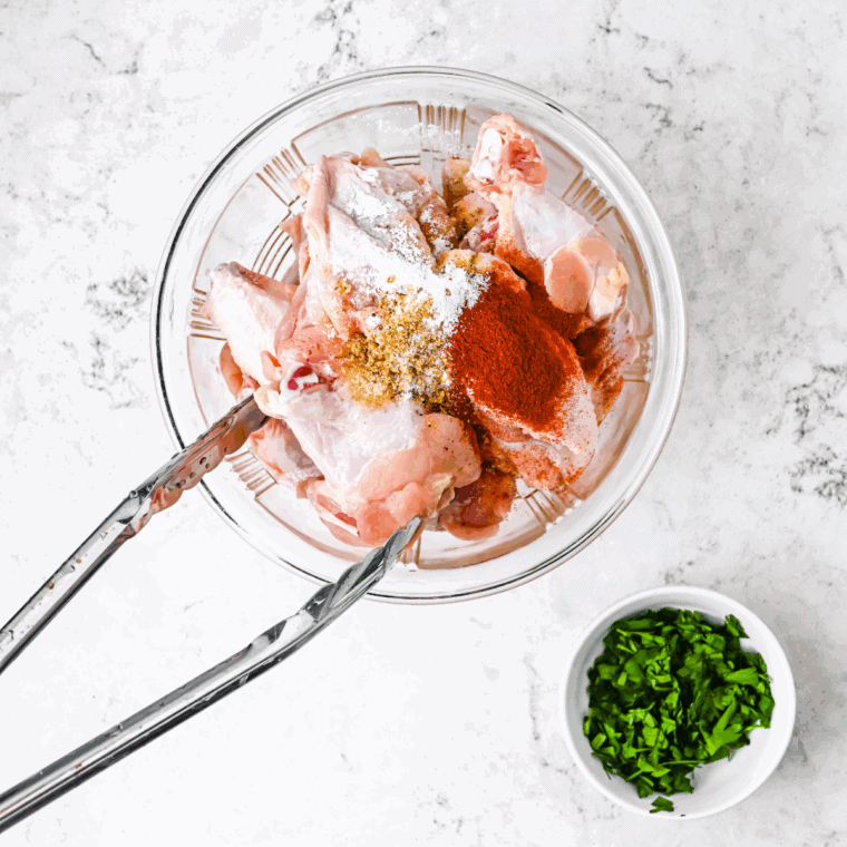 Tossing chicken wings in a bowl with cornstarch, salt, black pepper, and garlic powder to evenly coat.