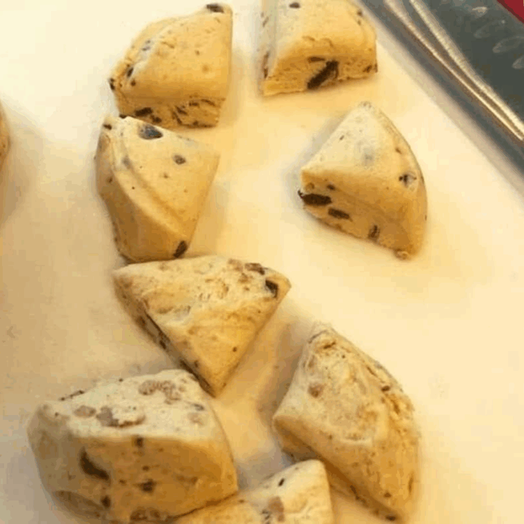 Cutting cinnamon rolls into four pieces on a wooden cutting board for bubble bites.
