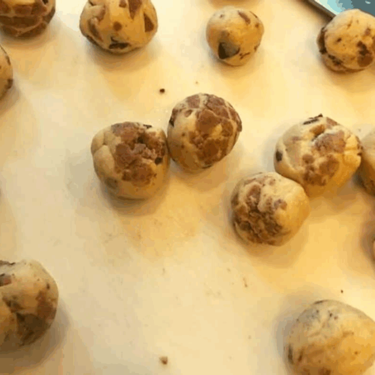Rolling cinnamon roll pieces into tight balls to prevent unrolling during baking.