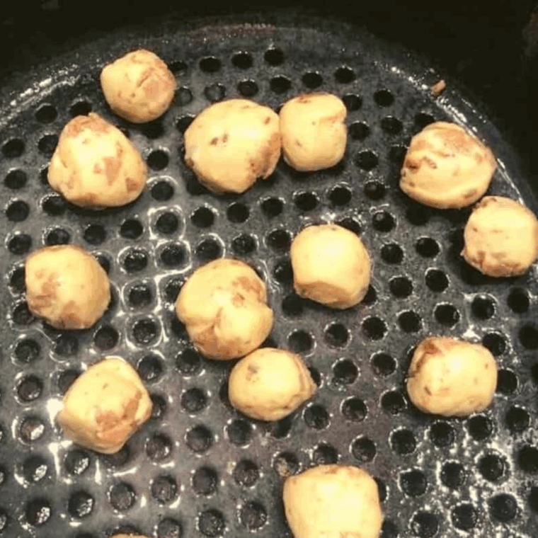 Spraying the air fryer basket with nonstick spray and cooking cinnamon roll bubble bites in two batches at 340°F.