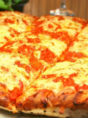 Air fryer Chicago style deep-dish pizza in a springform pan with one slice lifted, showing melted cheese beneath chunky tomato sauce.