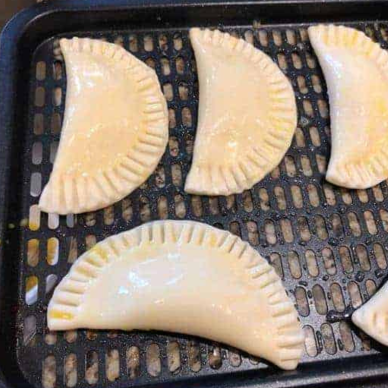 "Lemon hand pies cooking in the air fryer basket, turning golden brown."