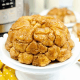 Air fryer monkey bread on a white plate with caramelized brown sugar glaze dripping down the pull-apart biscuit pieces