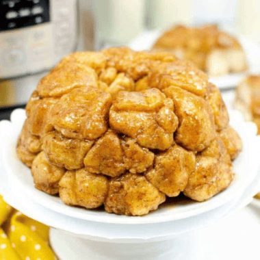 Air fryer monkey bread on a white plate with caramelized brown sugar glaze dripping down the pull-apart biscuit pieces