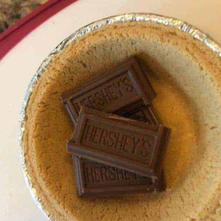 Assembling the Air Fryer S'mores Pie with layers of chocolate and marshmallows inside the crust.