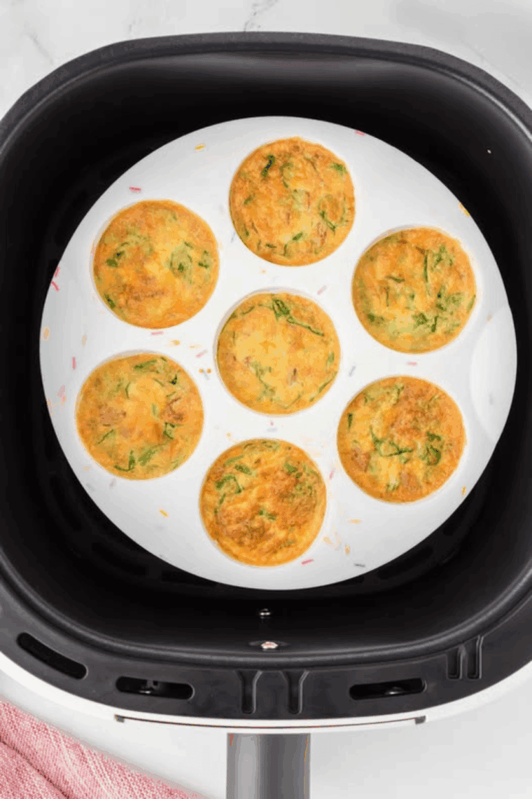 Air Fryer Western Omelet Egg Bites with ham, bell peppers, onions, and melted cheddar cheese served in a silicone mold for an easy breakfast.