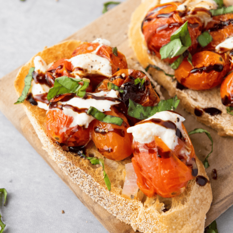 Fresh tomato and basil bruschetta topped with balsamic glaze on toasted baguette slices.