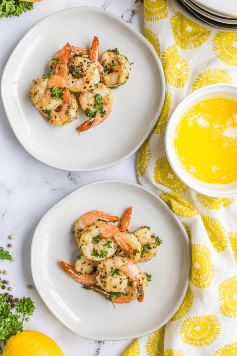 Golden-brown colossal garlic shrimp cooked in an air fryer, garnished with parsley and lemon wedges.