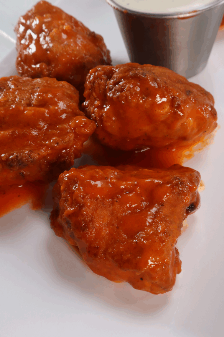 Plate of crispy boneless buffalo wings tossed in spicy sauce, served with celery and ranch dressing.
