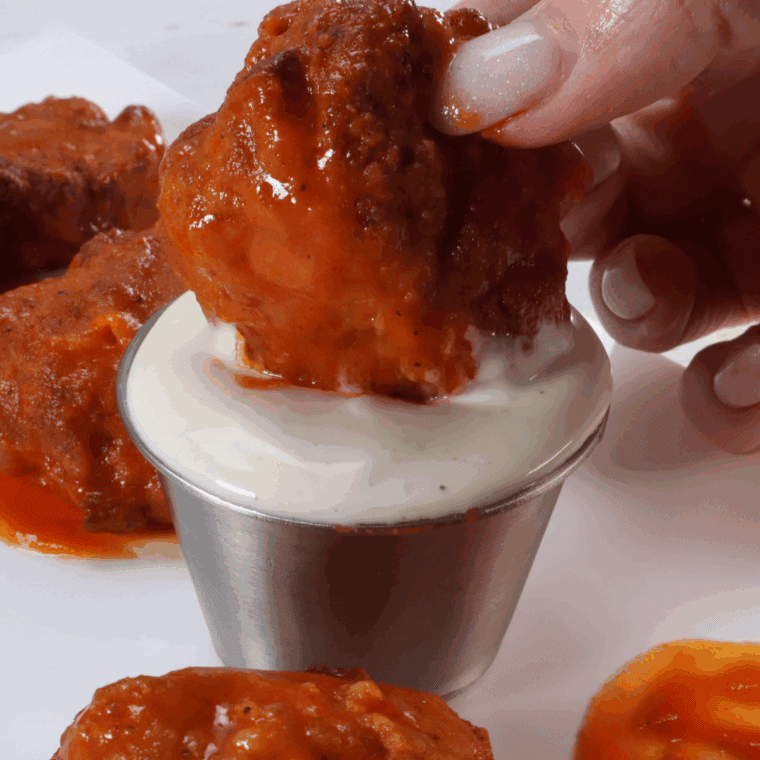 Plate of crispy boneless buffalo wings tossed in spicy sauce, served with celery and ranch dressing.