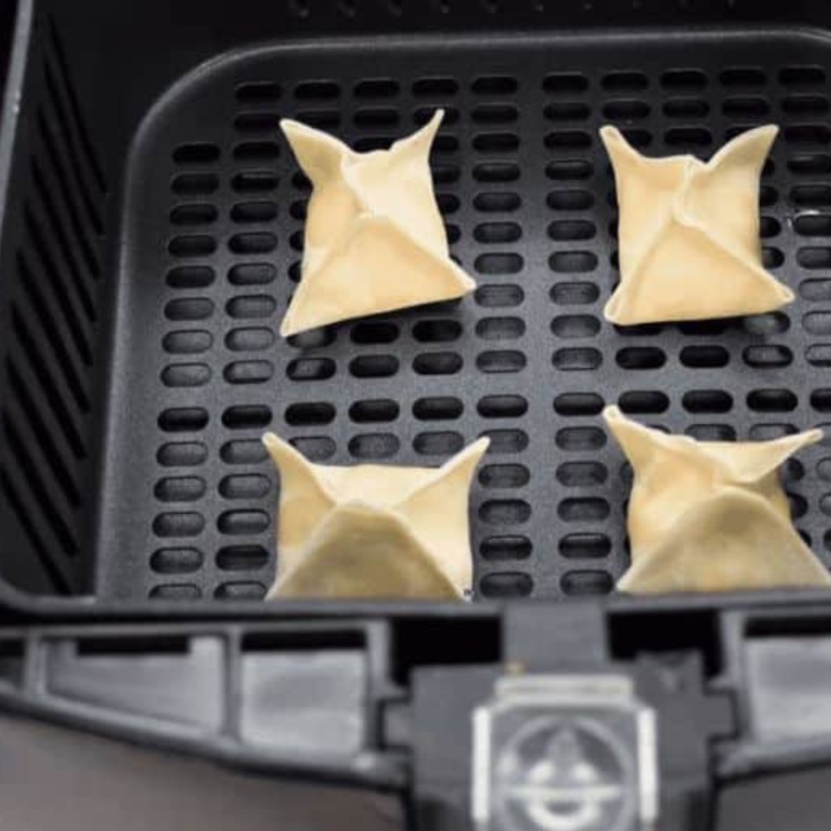  A hand folding and sealing a wonton wrapper, demonstrating the technique for making crab rangoon.